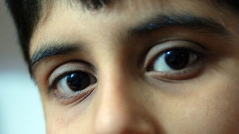 A close up of a boy's face, his dark eyes look into the camera